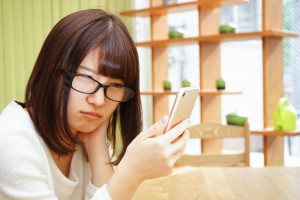 スマホを睨む眼鏡の女性