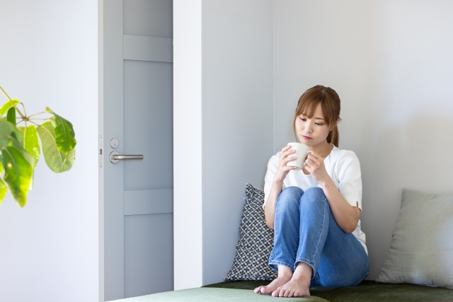 体育座りしてコーヒーを飲む女性