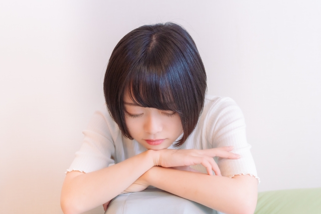 体育座りでうつむいている女性