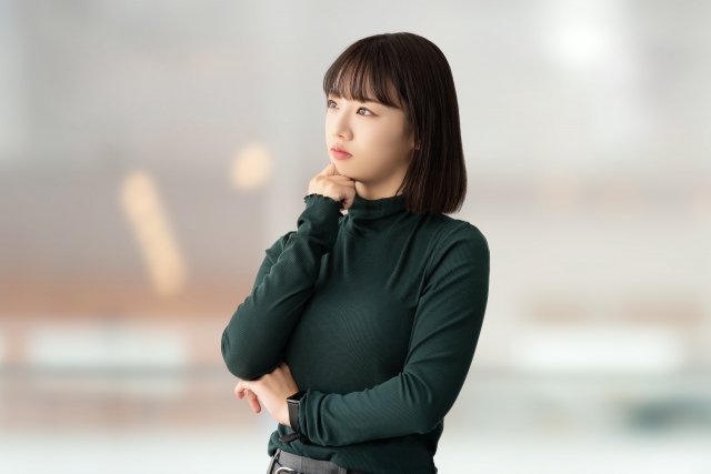 顎に手を当てて考えている女性