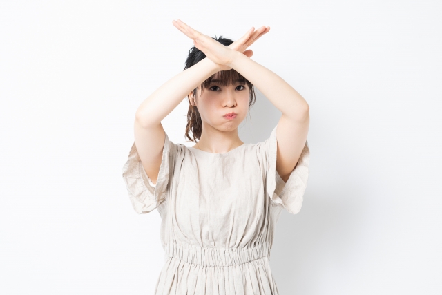 拒否や反対の気持ちを、腕を交差させて強く表現する女性。
