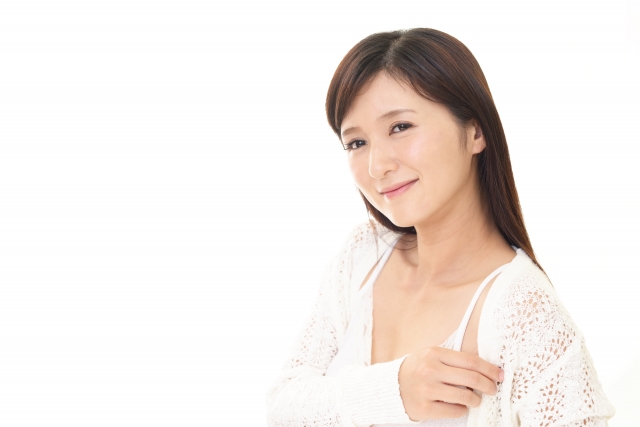  白のカーディガン姿の女性がやや肩を出しながら、少し色っぽく微笑んでいる上半身写真。